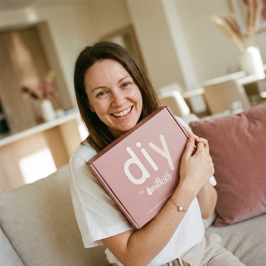 Glückliche Mutter zu Hause hält das DIY by MILKIES Kit im Arm – eine einfache, private Lösung, um ein armband muttermilch als persönliches Erinnerungsstück selbst zu gestalten.