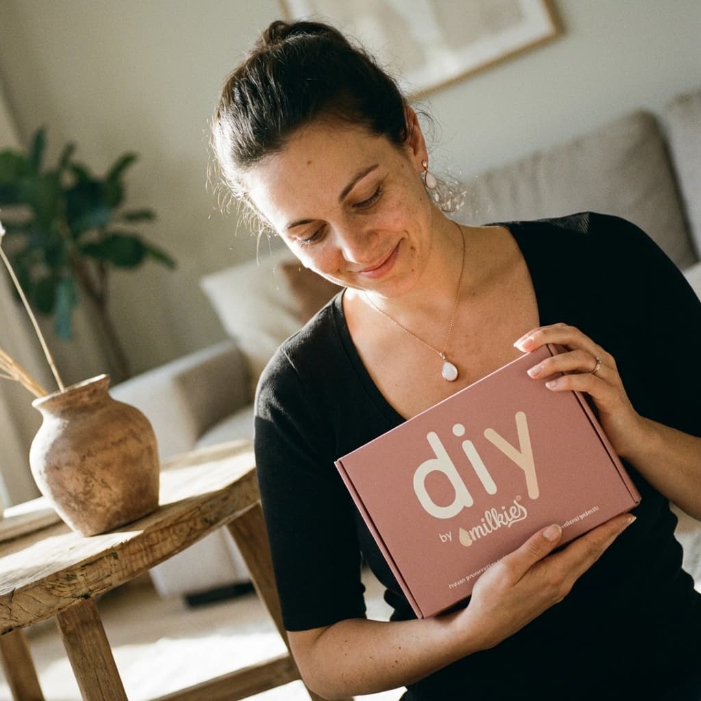 Glückliche Mutter hält eine „DIY by MILKIES“-Box in den Händen – Muttermilch Schmuck DIY als gute Idee, um zu Hause ein persönliches Erinnerungsstück selbst zu gestalten.
