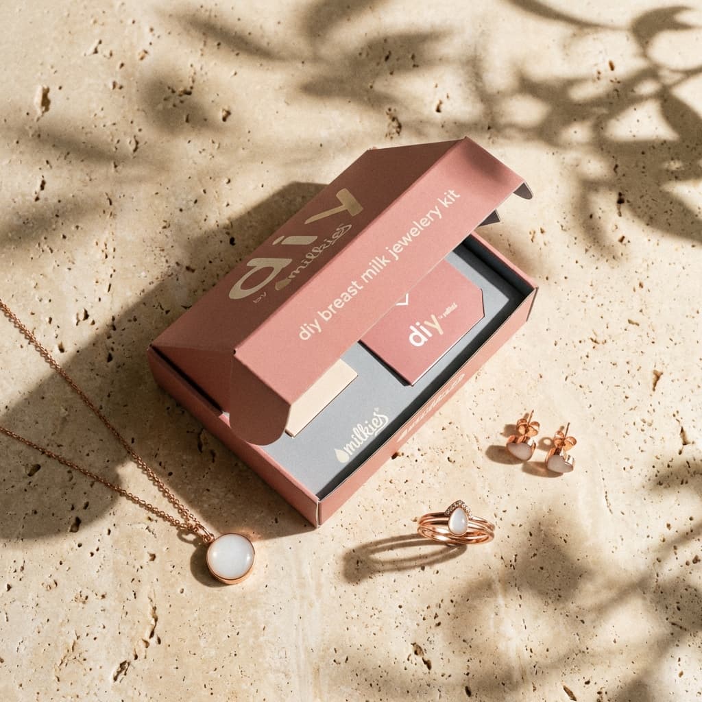 DIY by MILKIES Kit mit Schmuckstücken auf Steinoberfläche, Muttermilchschmuck selbst herstellen set in rosa Box mit roségoldenem Anhänger, Ring und Ohrringen